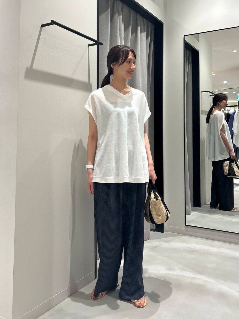 ベージュ系のかごバッグ、ホワイト系のニット/セーター、ゴールド系のサンダルを着用したレディースの夏コーディネートの2枚目の写真