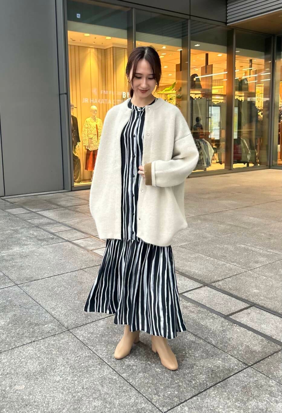 ベージュ系のブーツ、グレー系のカーディガン/ボレロ、ブラック系のワンピースを着用したレディースの冬コーディネートの2枚目の写真