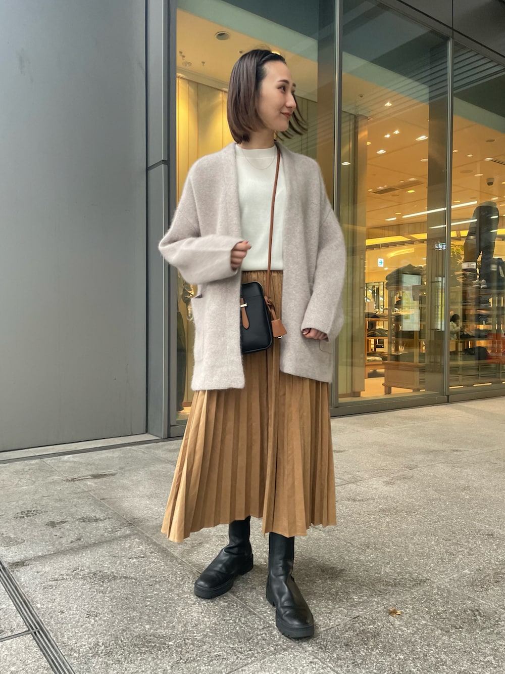 ベージュ系のカーディガン/ボレロ、ホワイト系のニット/セーター、イエロー系のスカートを着用したレディースの冬コーディネートの2枚目の写真