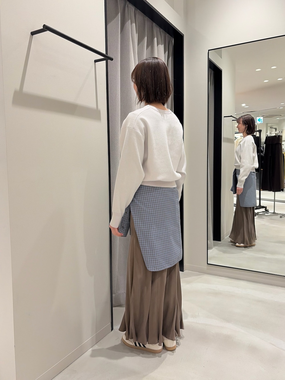 グレー系のニット/セーター、ブラウン系のスカート、ブルー系のシャツ/ブラウスを着用したレディースの冬コーディネートの3枚目の写真