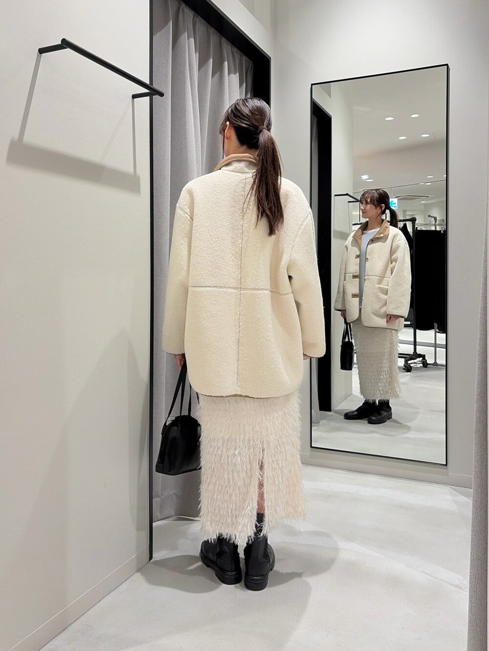 ホワイト系のムートンコート、ブルー系のニット/セーター、ホワイト系のTシャツ/カットソーを着用したレディースの冬コーディネートの3枚目の写真