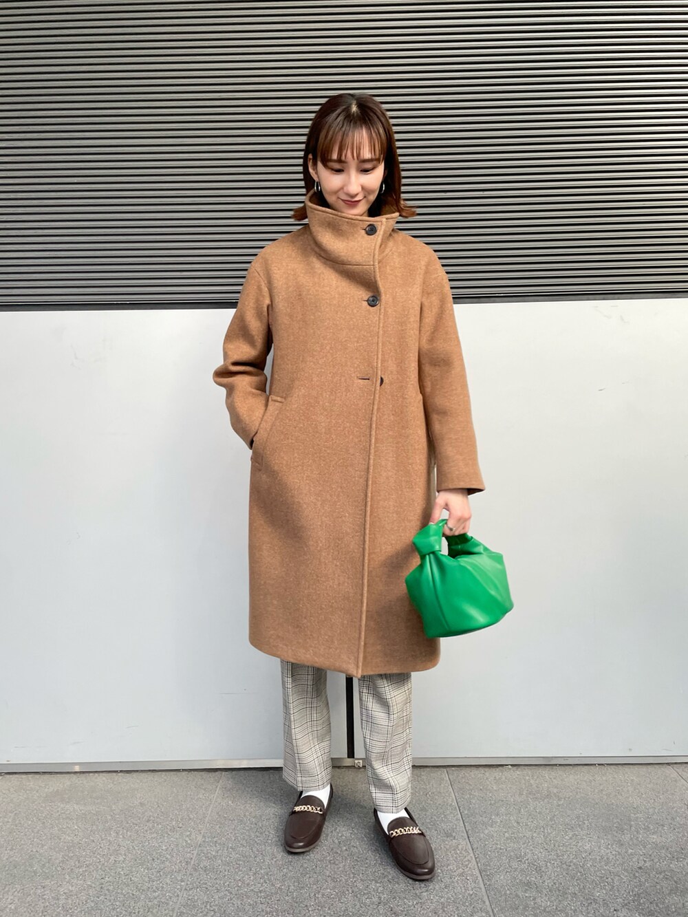 ベージュ系のその他アウター、ブラック系のニット/セーター、グリーン系のハンドバッグを着用したレディースの冬コーディネートの3枚目の写真