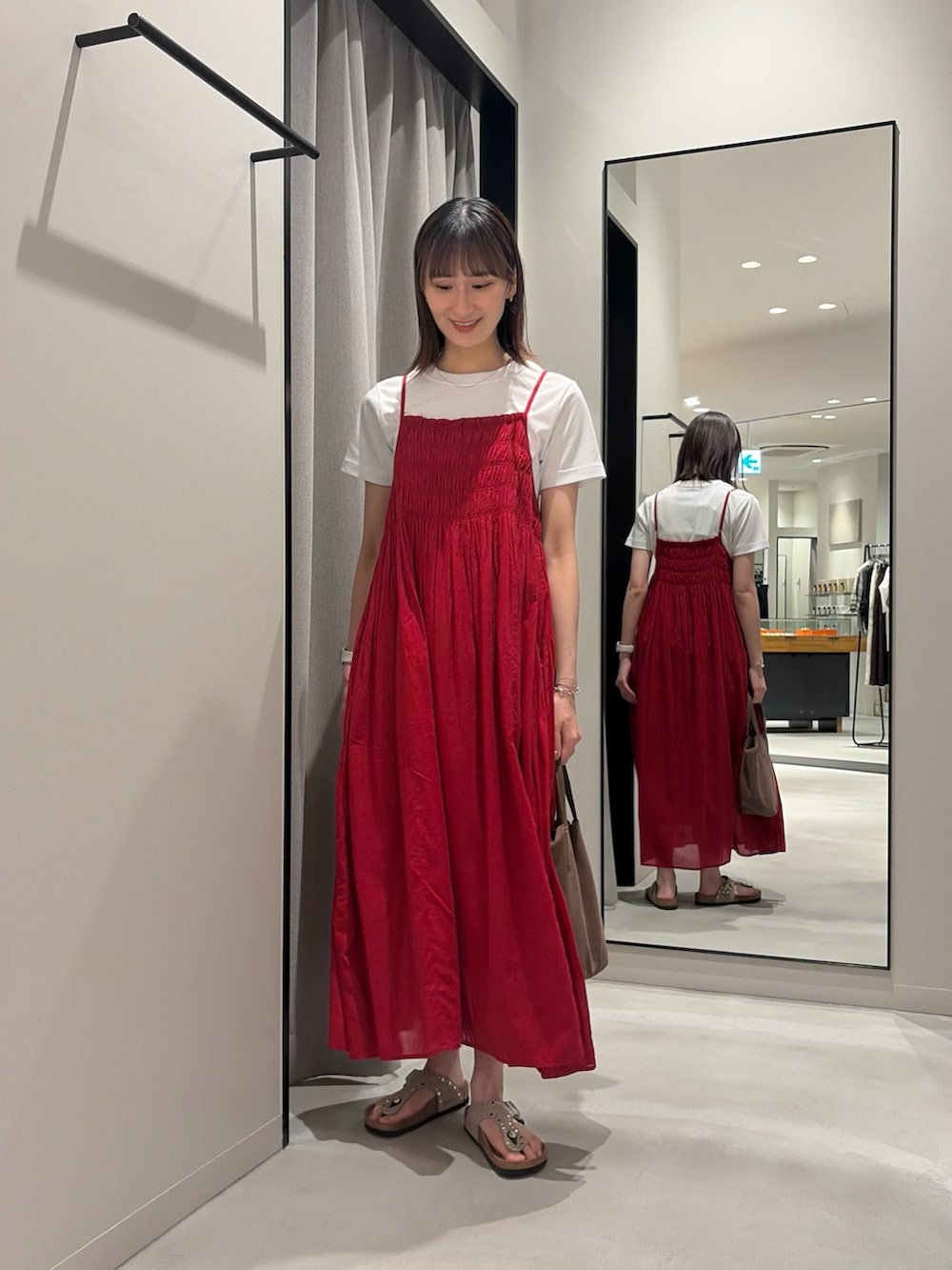 レッド系のワンピース、ホワイト系のTシャツ/カットソー、ベージュ系のサンダルを着用したレディースの春コーディネートの2枚目の写真