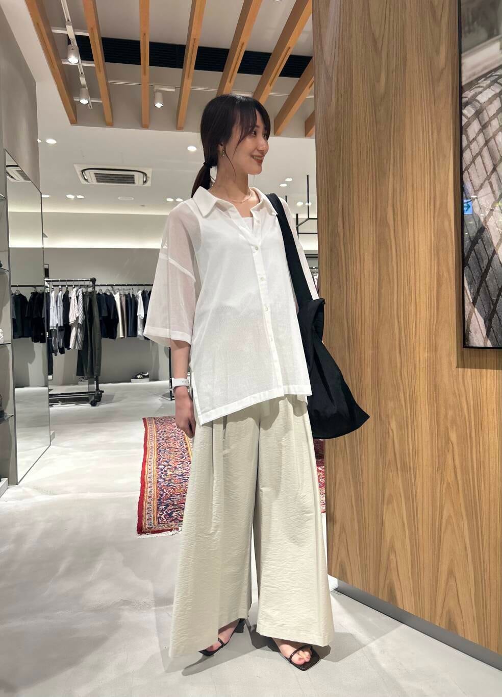 ホワイト系のタンクトップ、ブラック系のトートバッグ、ブラウン系のサンダルを着用したレディースの夏コーディネートの2枚目の写真