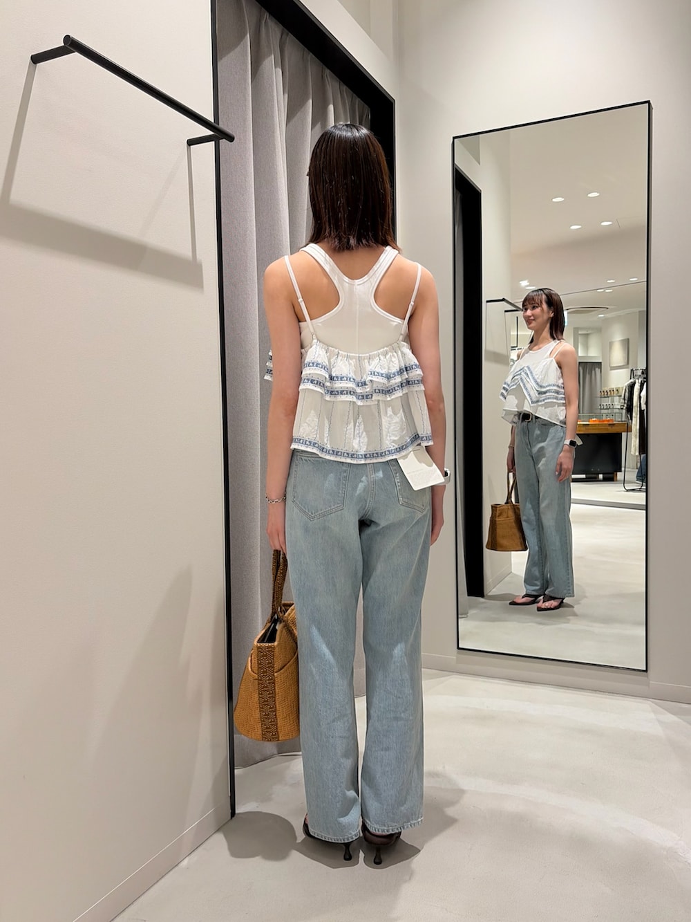 ブルー系のデニムパンツ、ブラウン系のサンダル、ベージュ系のバッグを着用したレディースの春コーディネートの2枚目の写真