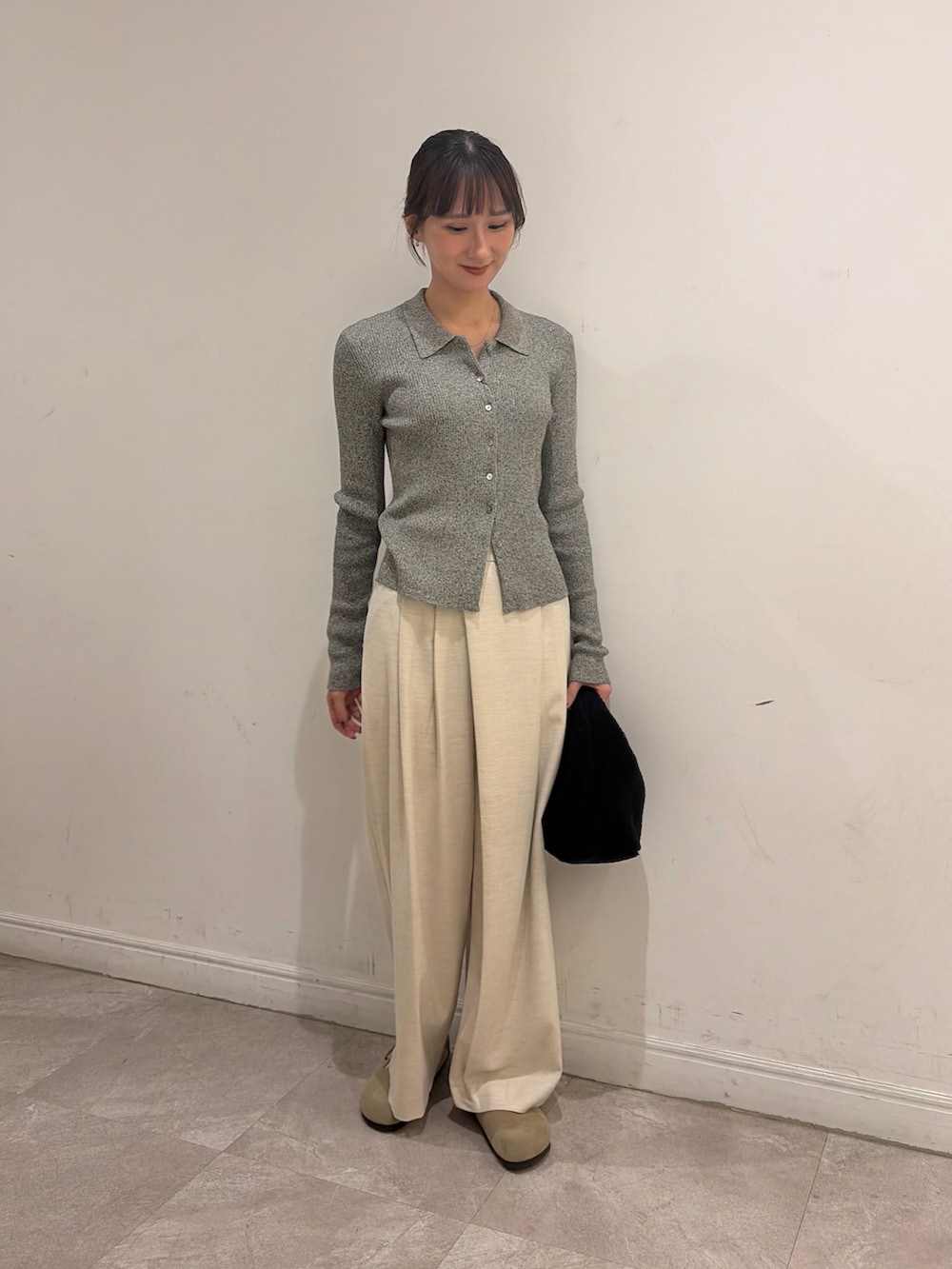 グレー系のニット/セーター、ホワイト系のその他パンツ、ブラック系のハンドバッグを着用したレディースの秋コーディネートの2枚目の写真