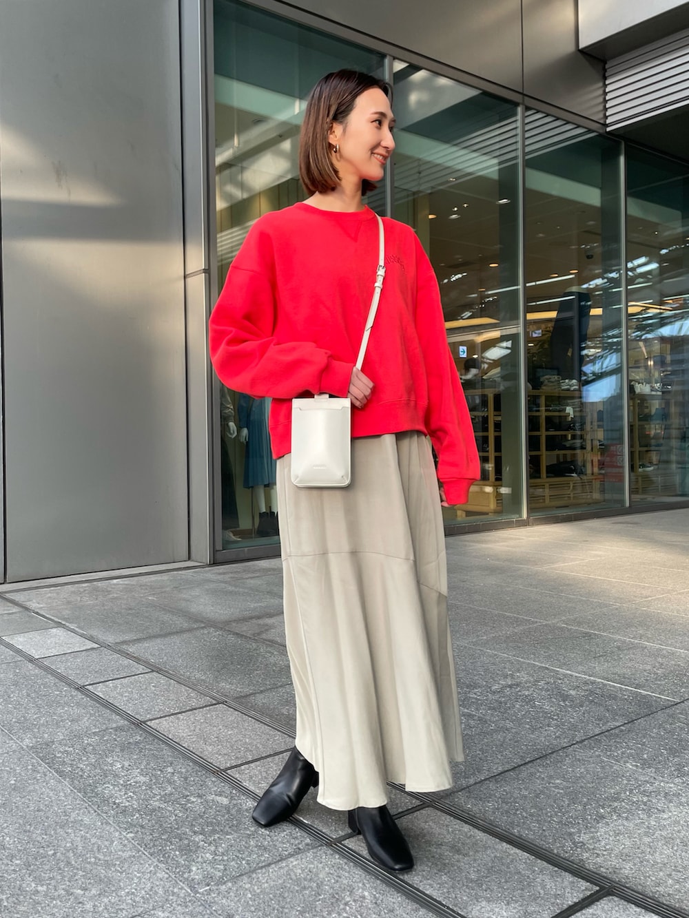 レッド系のスウェット、ベージュ系のワンピース、ブラック系のブーツを着用したレディースの冬コーディネートの3枚目の写真