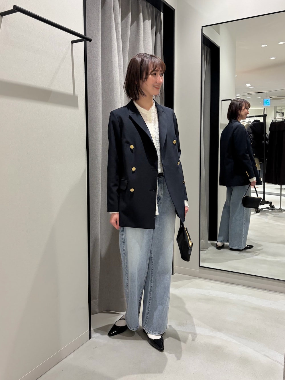 ブルー系のその他アウター、ホワイト系のシャツ/ブラウス、ブラック系のハンドバッグを着用したレディースの冬コーディネートの2枚目の写真