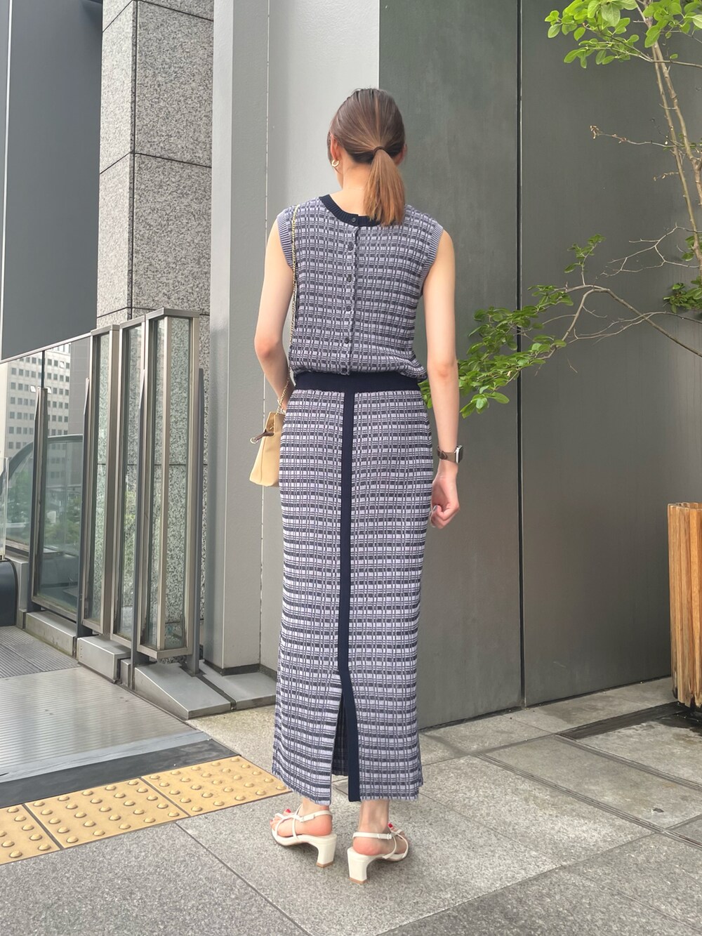 ブルー系のニット/セーター、ブルー系のスカート、ホワイト系のサンダルを着用したレディースの夏コーディネートの2枚目の写真