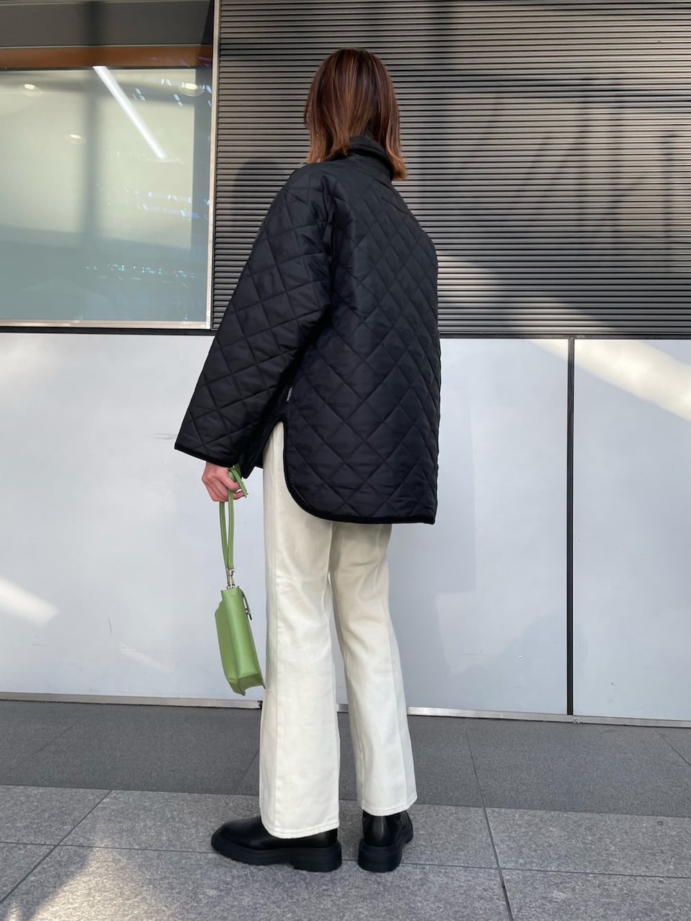 ブラック系のダウンジャケット/コート、ホワイト系のニット/セーター、ホワイト系のデニムパンツを着用したレディースの秋コーディネートの2枚目の写真