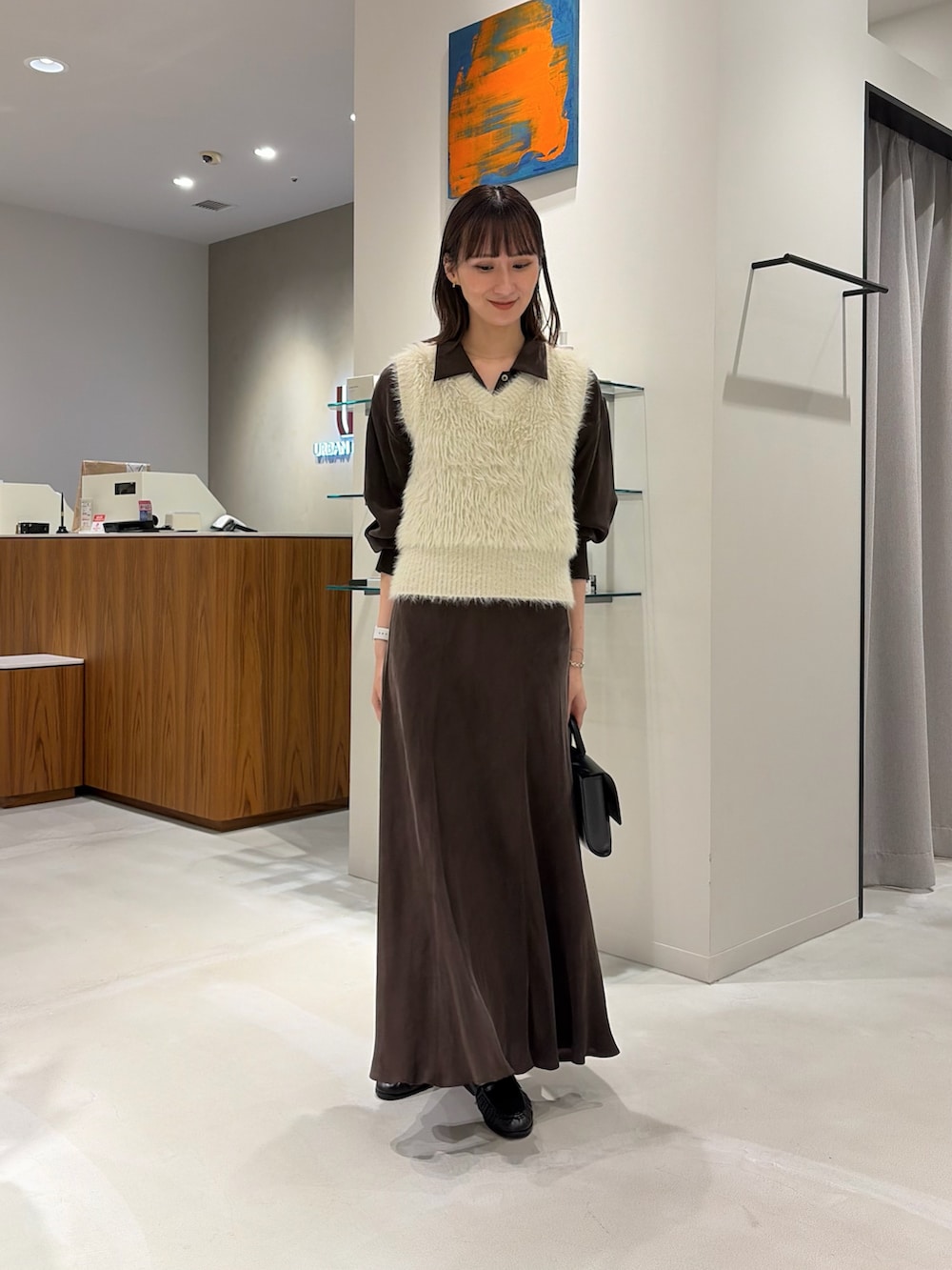 ブラウン系のシャツ/ブラウス、ブラウン系のスカート、ブラック系のハンドバッグを着用したレディースの秋コーディネートの2枚目の写真