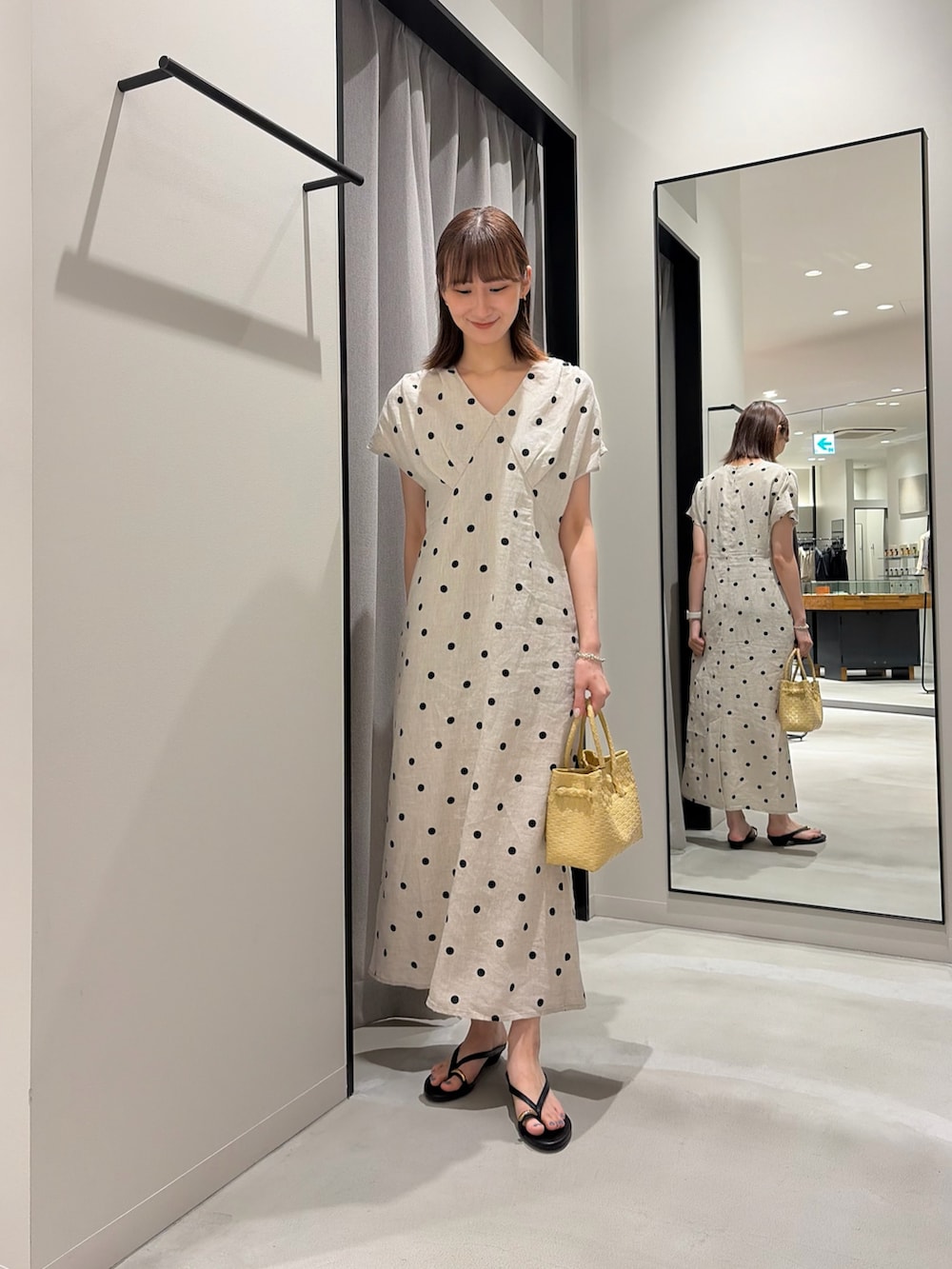 ブラック系のサンダル、ベージュ系のワンピース、ベージュ系のトートバッグを着用したレディースの夏コーディネートの2枚目の写真