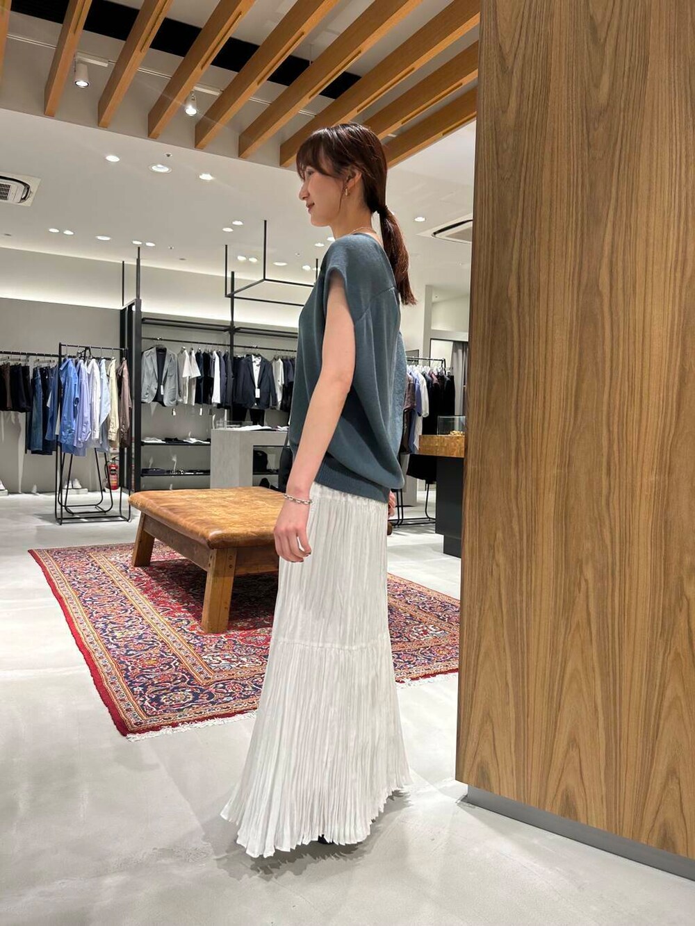 ホワイト系のスカート、ブラウン系のサンダル、ブルー系のベストを着用したレディースの春コーディネートの3枚目の写真