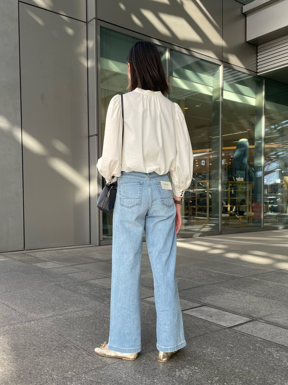 ホワイト系のシャツ/ブラウス、ブルー系のデニムパンツ、ブラック系のショルダーバッグを着用したレディースの春コーディネートの3枚目の写真