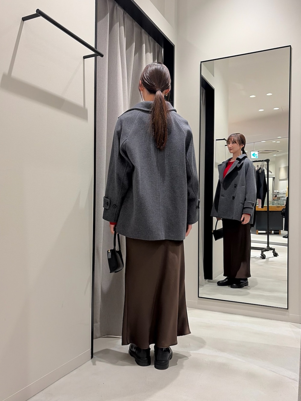 グレー系のピーコート、レッド系のニット/セーター、ブラウン系のスカートを着用したレディースの冬コーディネートの3枚目の写真