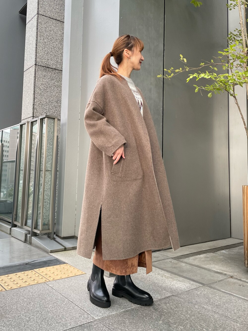 グレー系のその他アウター、グレー系のニット/セーター、ブラウン系のスカートを着用したレディースの秋コーディネートの2枚目の写真