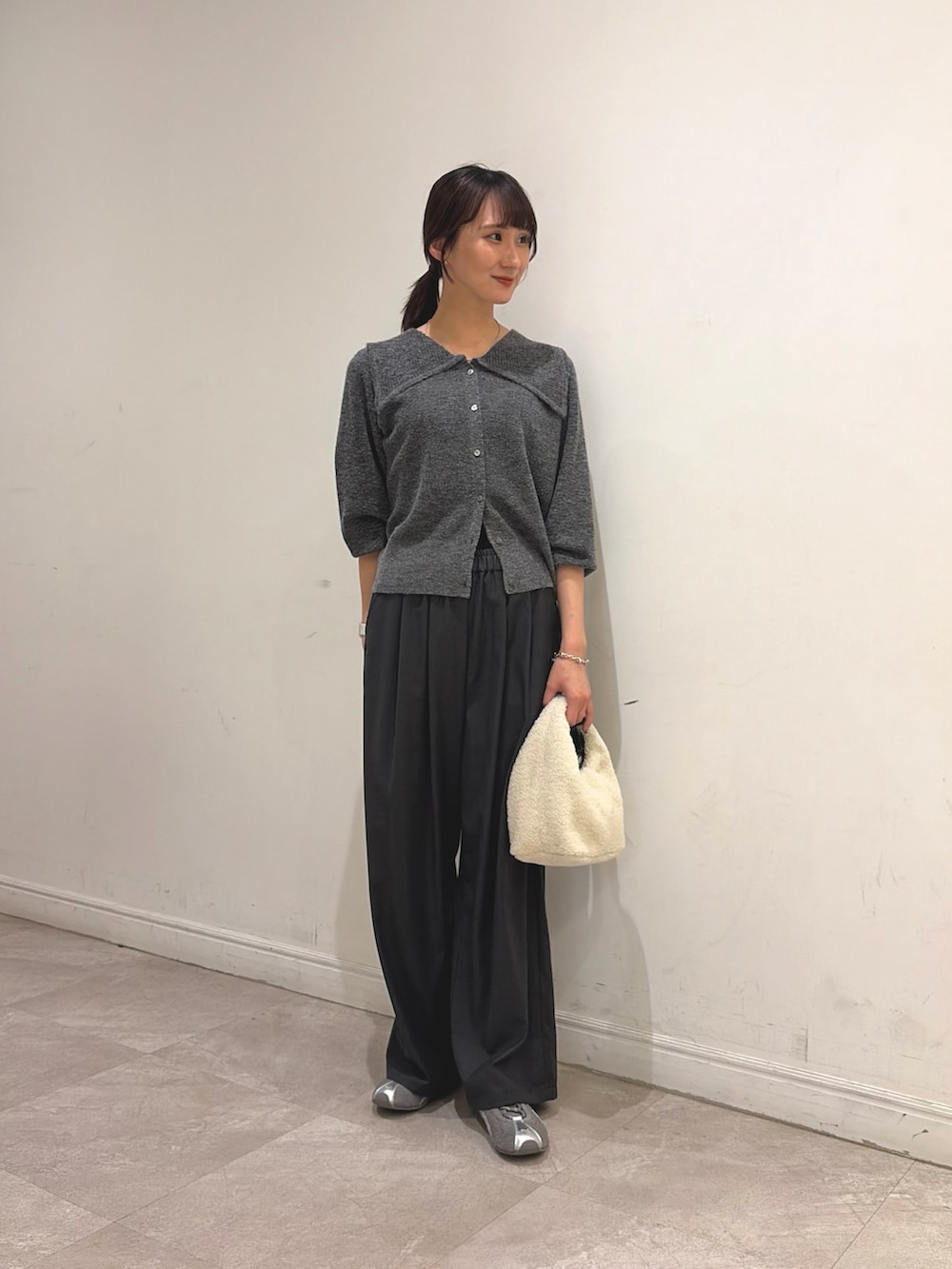 グレー系のニット/セーター、グレー系のその他パンツ、ホワイト系のハンドバッグを着用したレディースの秋コーディネートの2枚目の写真
