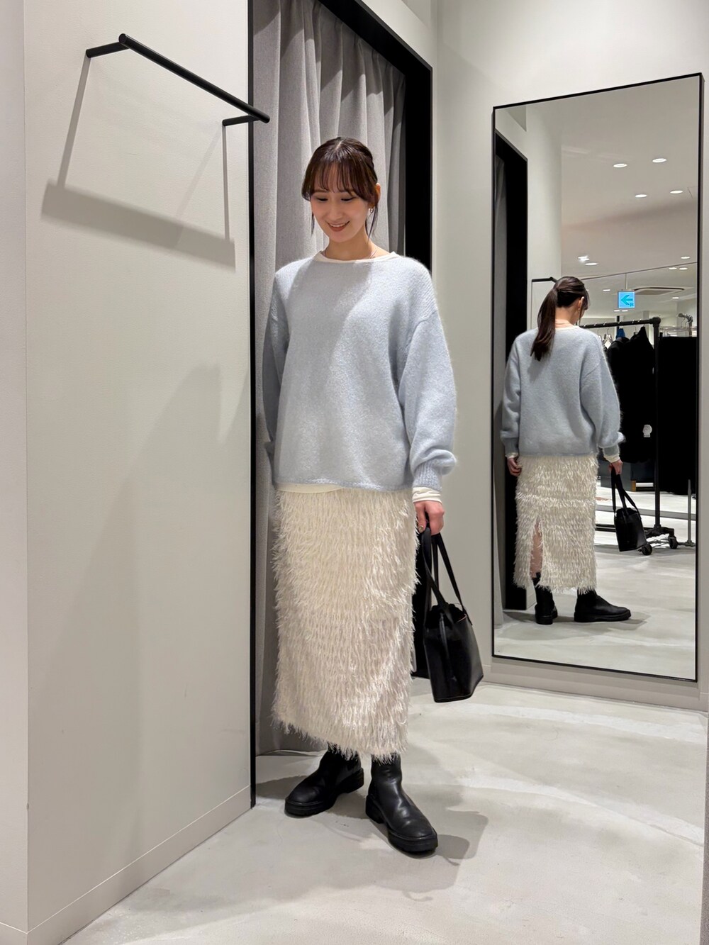 ホワイト系のムートンコート、ブルー系のニット/セーター、ホワイト系のTシャツ/カットソーを着用したレディースの冬コーディネートの6枚目の写真
