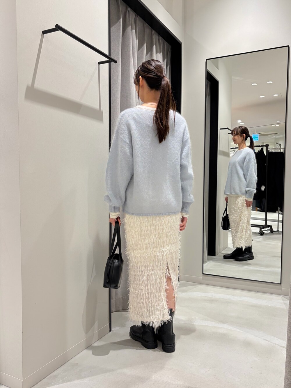 ホワイト系のムートンコート、ブルー系のニット/セーター、ホワイト系のTシャツ/カットソーを着用したレディースの冬コーディネートの8枚目の写真