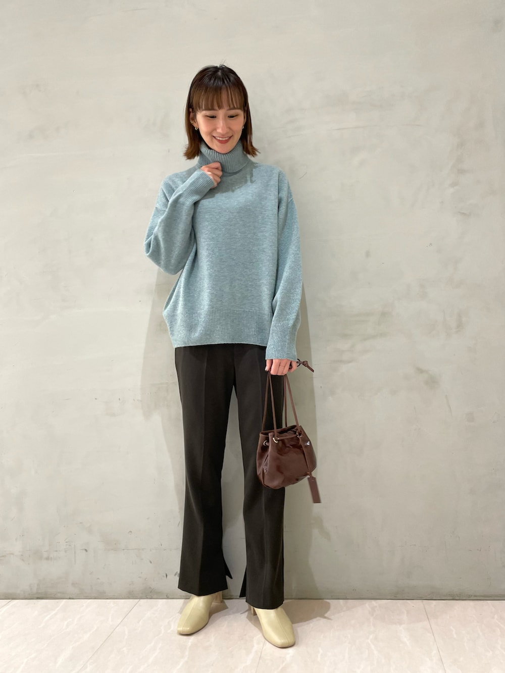 ベージュ系のその他アウター、グリーン系のニット/セーター、ブラウン系のハンドバッグを着用したレディースの冬コーディネートの2枚目の写真