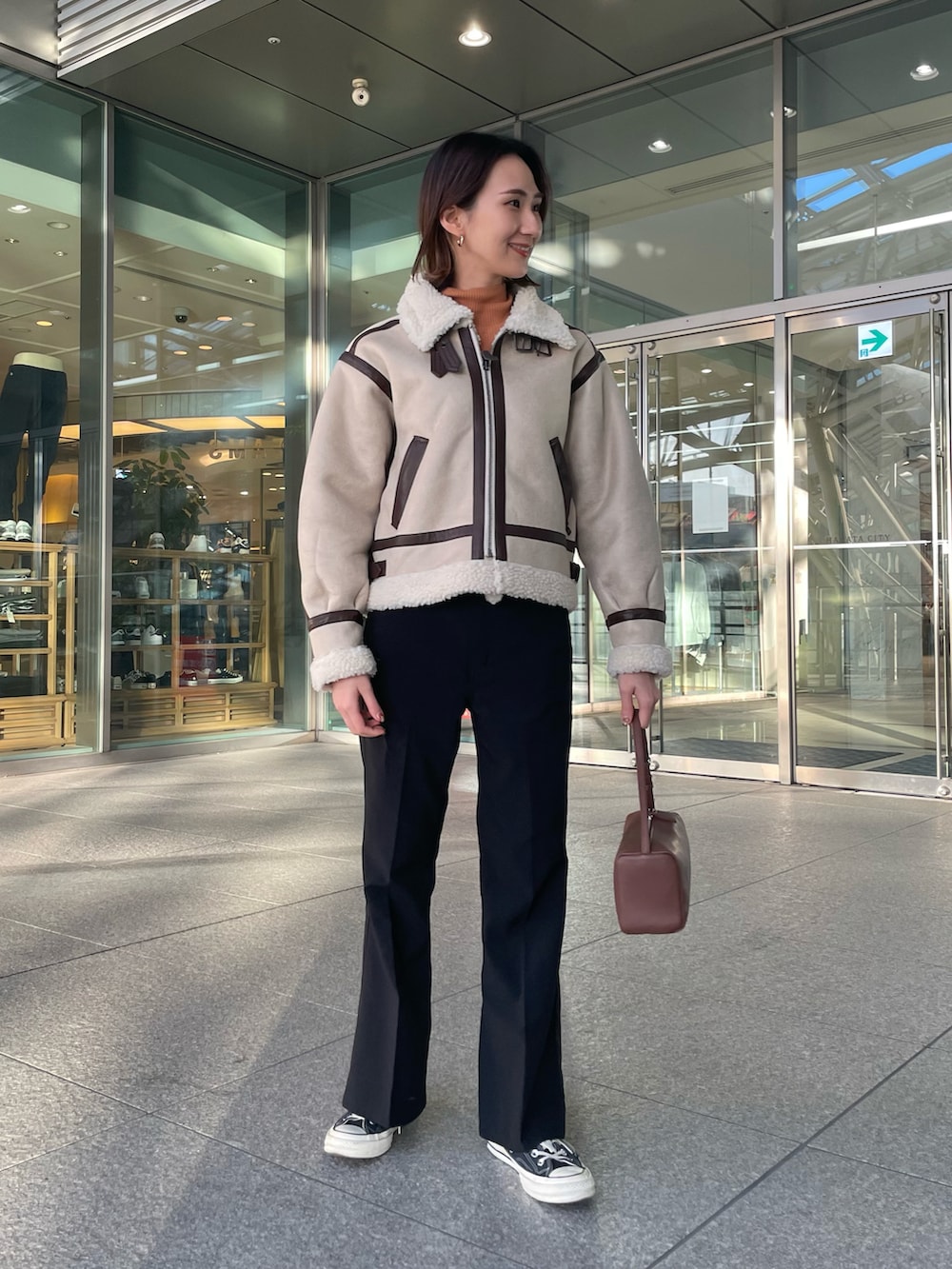 ベージュ系のブルゾン、ブラック系のその他パンツ、ブラウン系のボストンバッグを着用したレディースの冬コーディネートの2枚目の写真