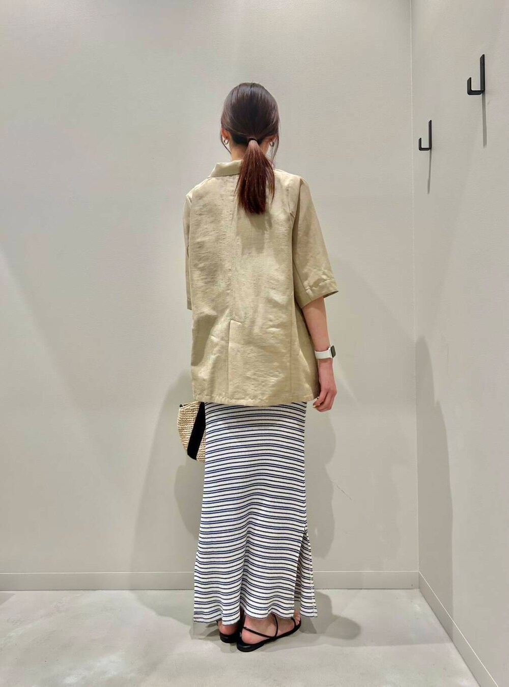 ベージュ系のかごバッグ、ベージュ系のその他アウター、ブラック系のサンダルを着用したレディースの春コーディネートの3枚目の写真