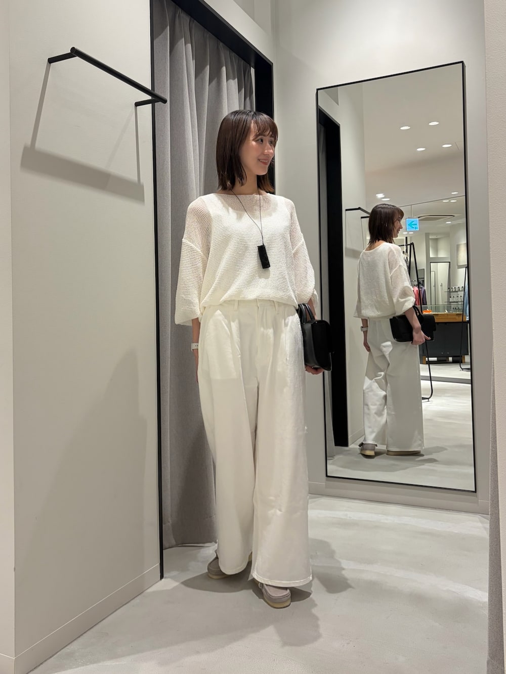 ホワイト系のデニムパンツ、ブラック系のハンドバッグ、グレー系のその他シューズを着用したレディースの春コーディネートの2枚目の写真