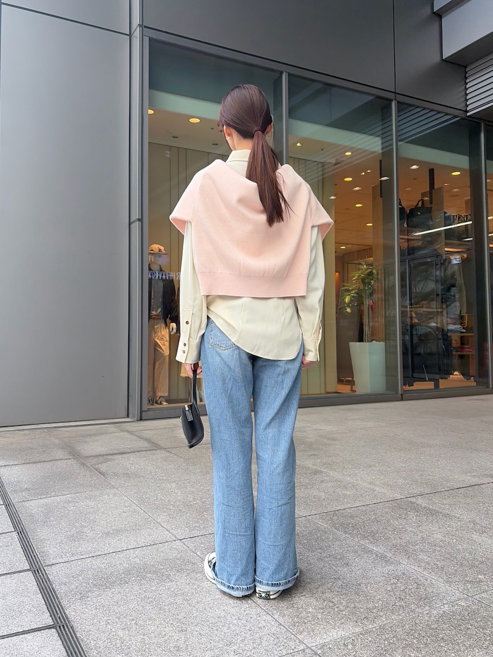 ピンク系のニット/セーター、ホワイト系のシャツ/ブラウス、ブラック系のハンドバッグを着用したレディースの冬コーディネートの2枚目の写真