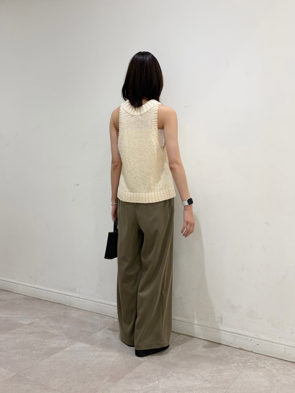 ホワイト系のベスト、グリーン系のその他パンツ、ブラック系のハンドバッグを着用したレディースの夏コーディネートの3枚目の写真