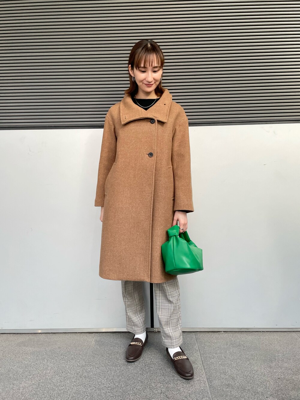ベージュ系のその他アウター、ブラック系のニット/セーター、グリーン系のハンドバッグを着用したレディースの冬コーディネートの2枚目の写真