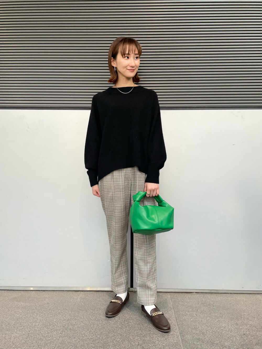 ベージュ系のその他アウター、ブラック系のニット/セーター、グリーン系のハンドバッグを着用したレディースの冬コーディネートの4枚目の写真