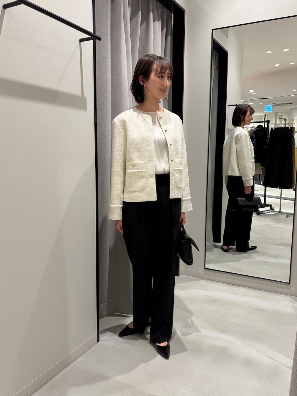 ホワイト系のシャツ/ブラウス、ホワイト系のノーカラージャケット、ブラック系のハンドバッグを着用したレディースの冬コーディネートの2枚目の写真