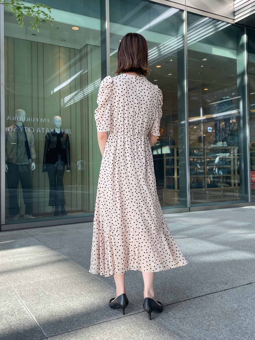 ベージュ系のワンピース、ブラック系のパンプス、ホワイト系のショルダーバッグを着用したレディースの秋コーディネートの2枚目の写真