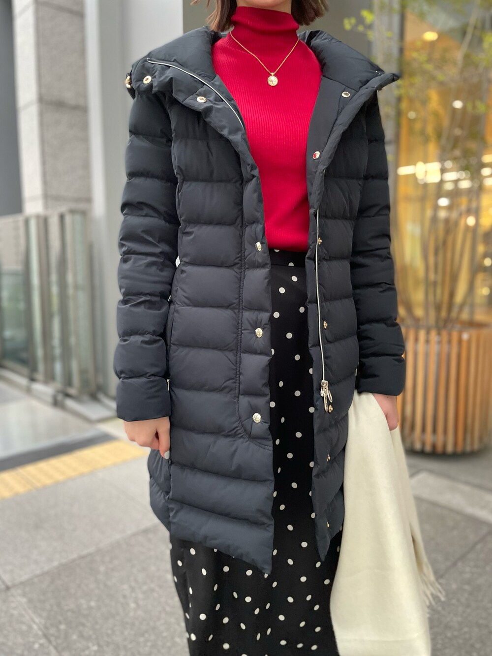 ブラック系のダウンジャケット/コート、レッド系のニット/セーター、ブラック系のスカートを着用したレディースの冬コーディネートの4枚目の写真