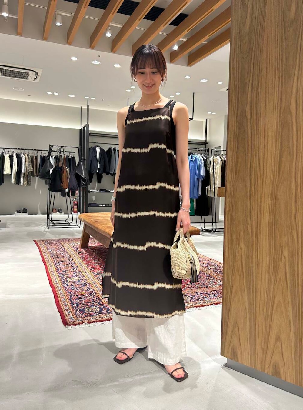 ベージュ系のかごバッグ、ブラック系のタンクトップ、ホワイト系のその他パンツを着用したレディースの夏コーディネートの2枚目の写真