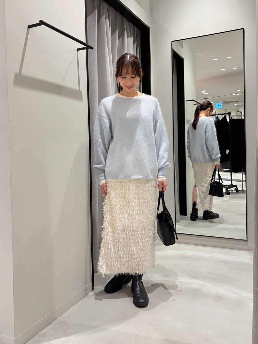ホワイト系のムートンコート、ブルー系のニット/セーター、ホワイト系のTシャツ/カットソーを着用したレディースの冬コーディネートの7枚目の写真