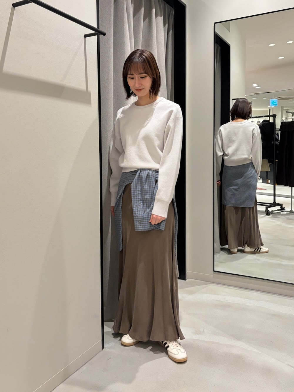 グレー系のニット/セーター、ブラウン系のスカート、ブルー系のシャツ/ブラウスを着用したレディースの冬コーディネートの2枚目の写真