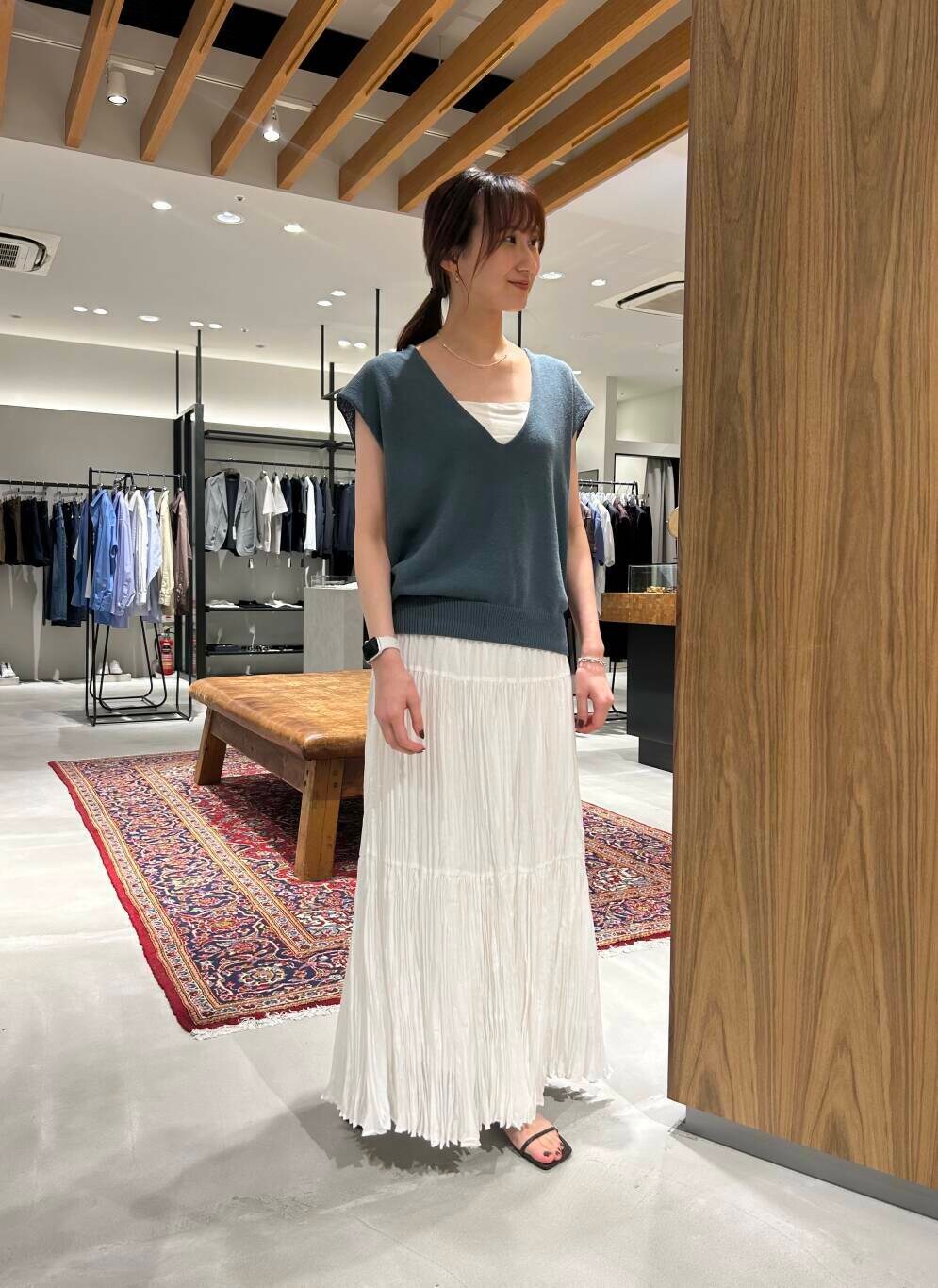 ホワイト系のスカート、ブラウン系のサンダル、ブルー系のベストを着用したレディースの春コーディネートの2枚目の写真