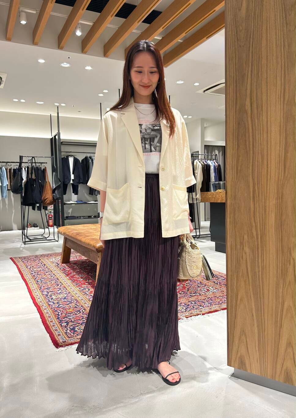 ベージュ系のかごバッグ、ブラウン系のスカート、ブラック系のサンダルを着用したレディースの夏コーディネートの2枚目の写真