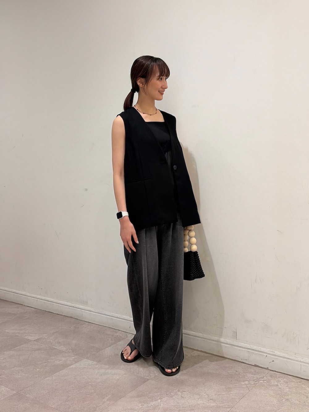 ブラック系のデニムパンツ、ブラック系のタンクトップ、ブラック系のダウンベストを着用したレディースの夏コーディネートの2枚目の写真