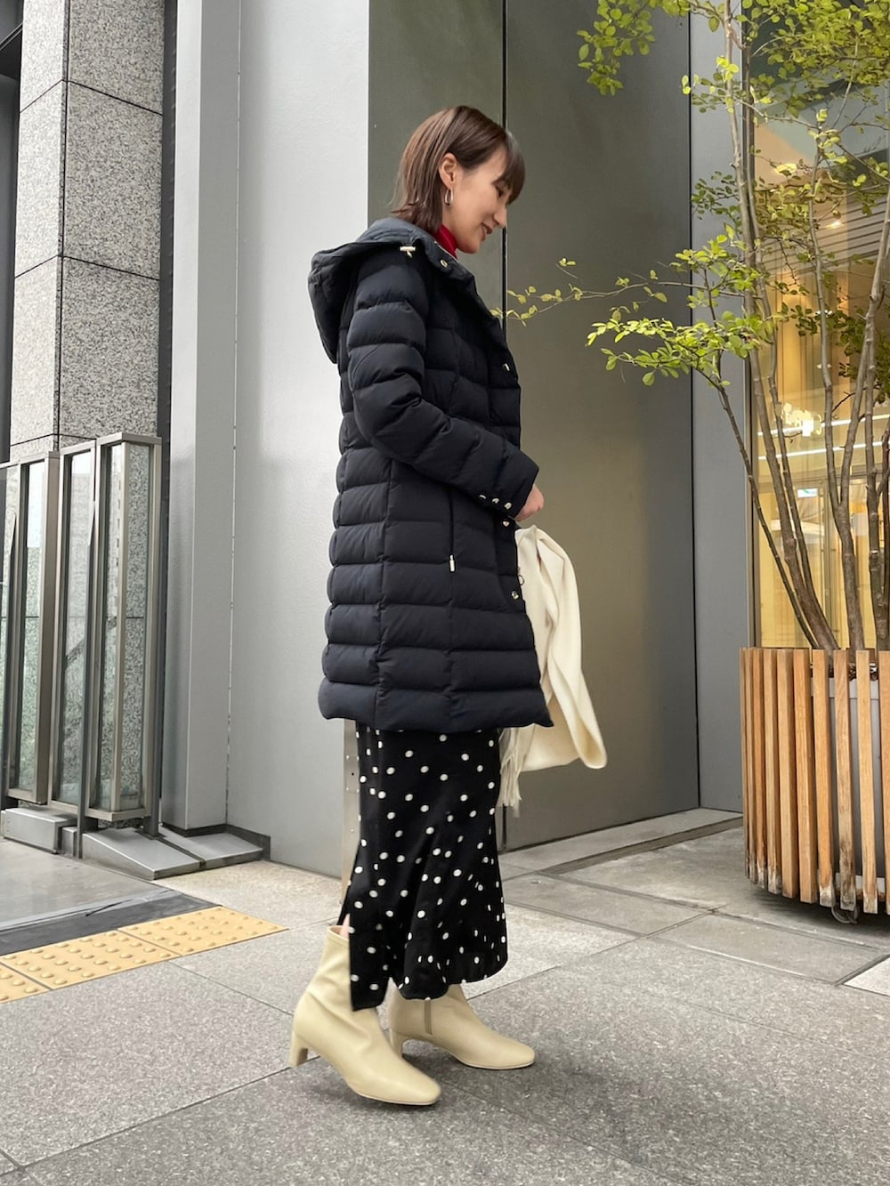 ブラック系のダウンジャケット/コート、レッド系のニット/セーター、ブラック系のスカートを着用したレディースの冬コーディネートの2枚目の写真