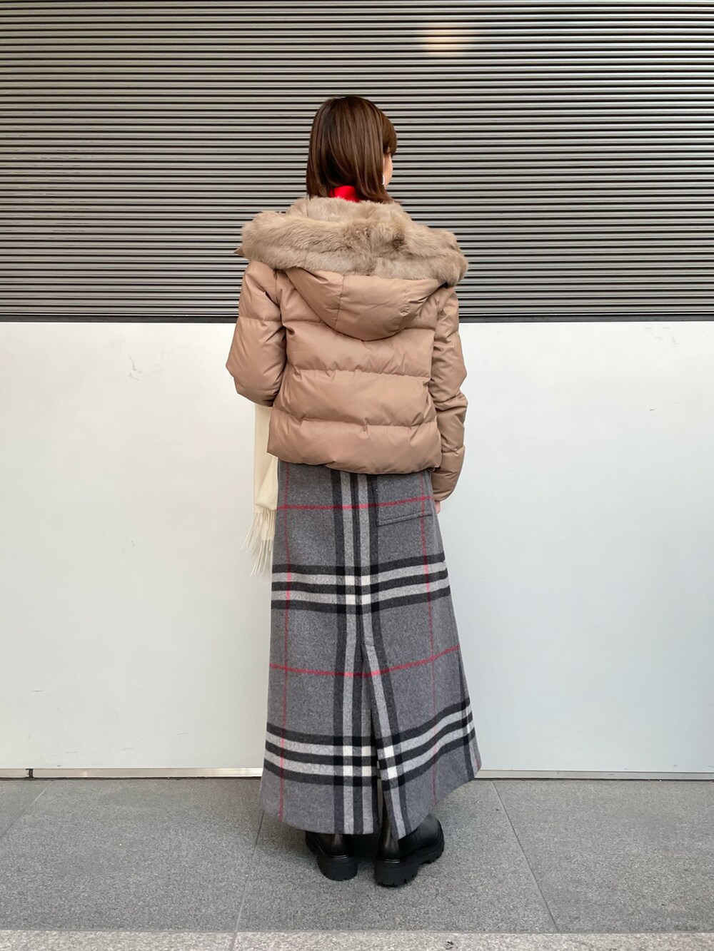 ベージュ系のダウンジャケット/コート、ブラック系のブーツ、ホワイト系のマフラーを着用したレディースの冬コーディネートの2枚目の写真