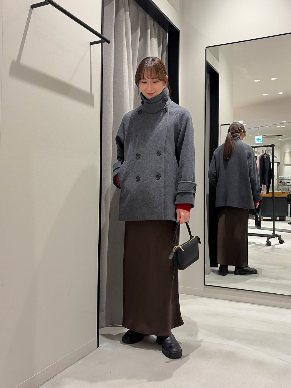 グレー系のピーコート、レッド系のニット/セーター、ブラウン系のスカートを着用したレディースの冬コーディネートの2枚目の写真