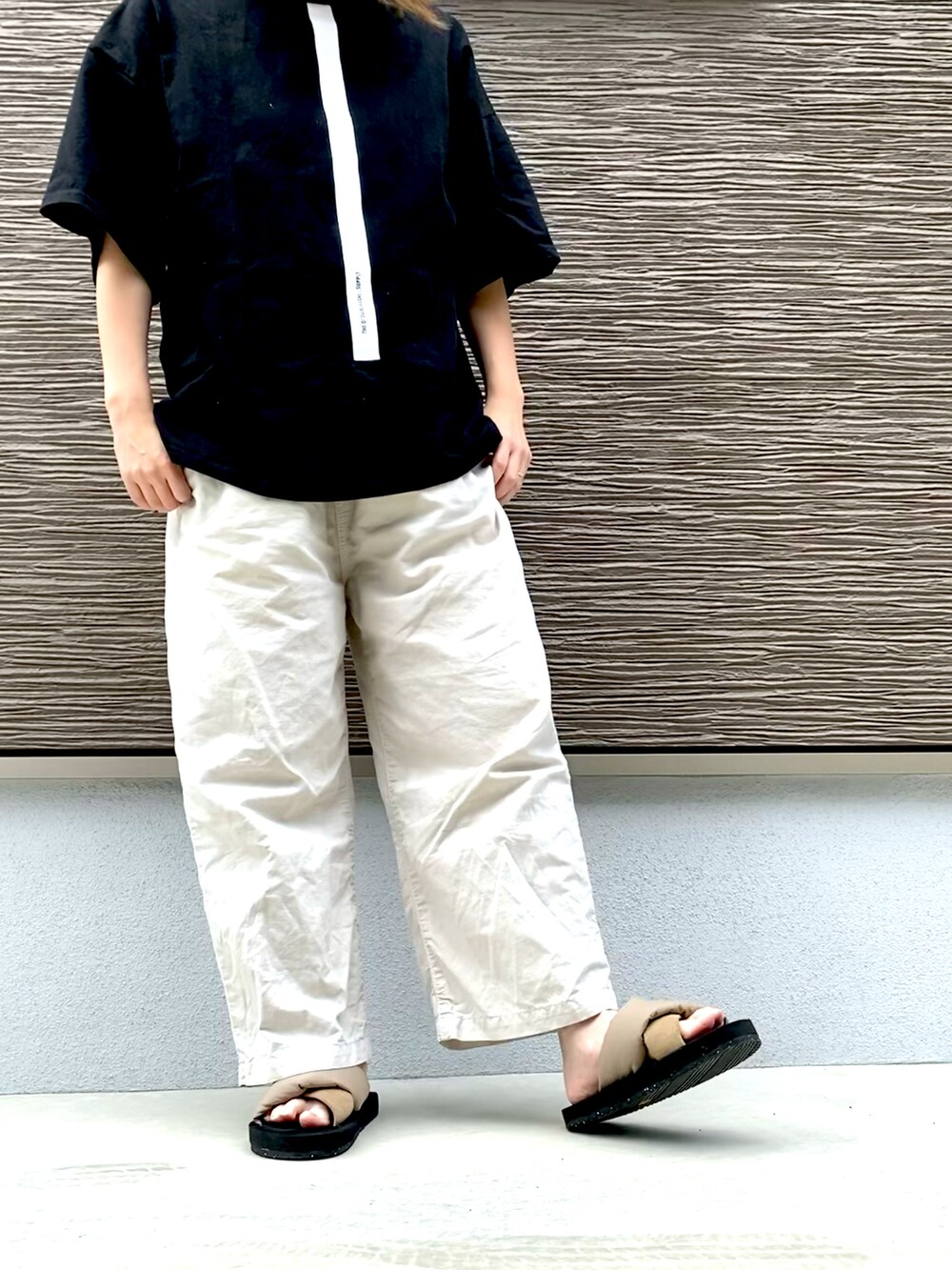 ブラック系のTシャツ/カットソー、ベージュ系のパンツ、ベージュ系のサンダルを着用したレディースの夏コーディネートの2枚目の写真