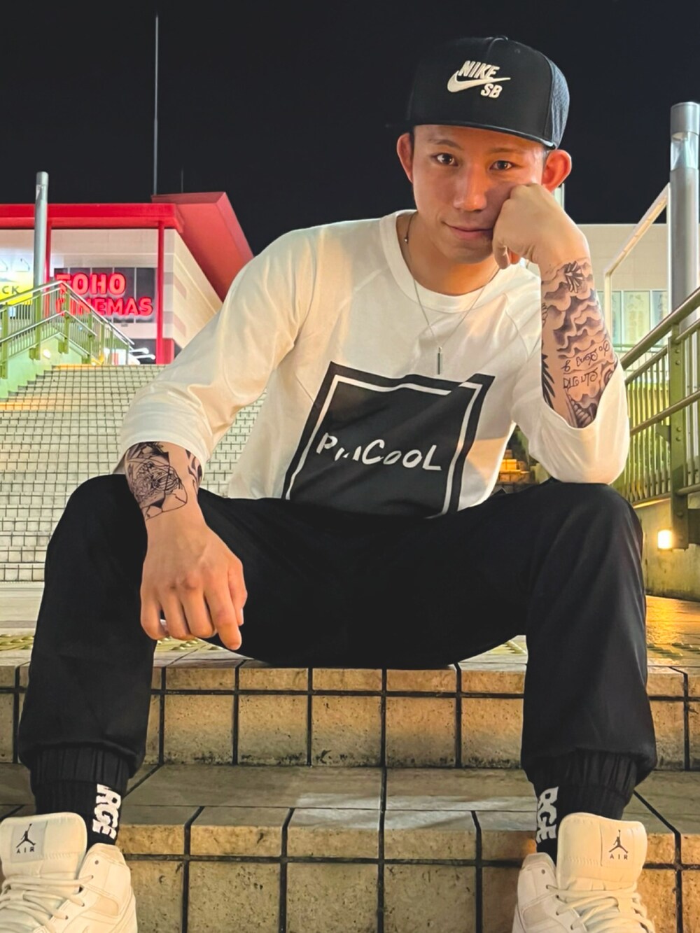 ホワイト系のスニーカー、ホワイト系のTシャツ/カットソー、ブラック系のカーゴパンツを着用したメンズの春コーディネートの2枚目の写真