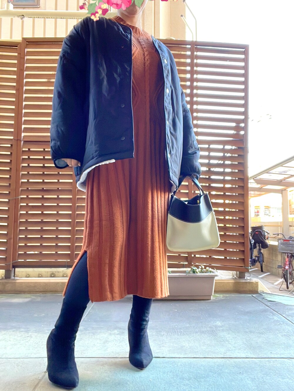 ブラウン系のワンピース、ブラック系のブーツ、ホワイト系のブルゾンを着用したレディースの冬コーディネートの2枚目の写真