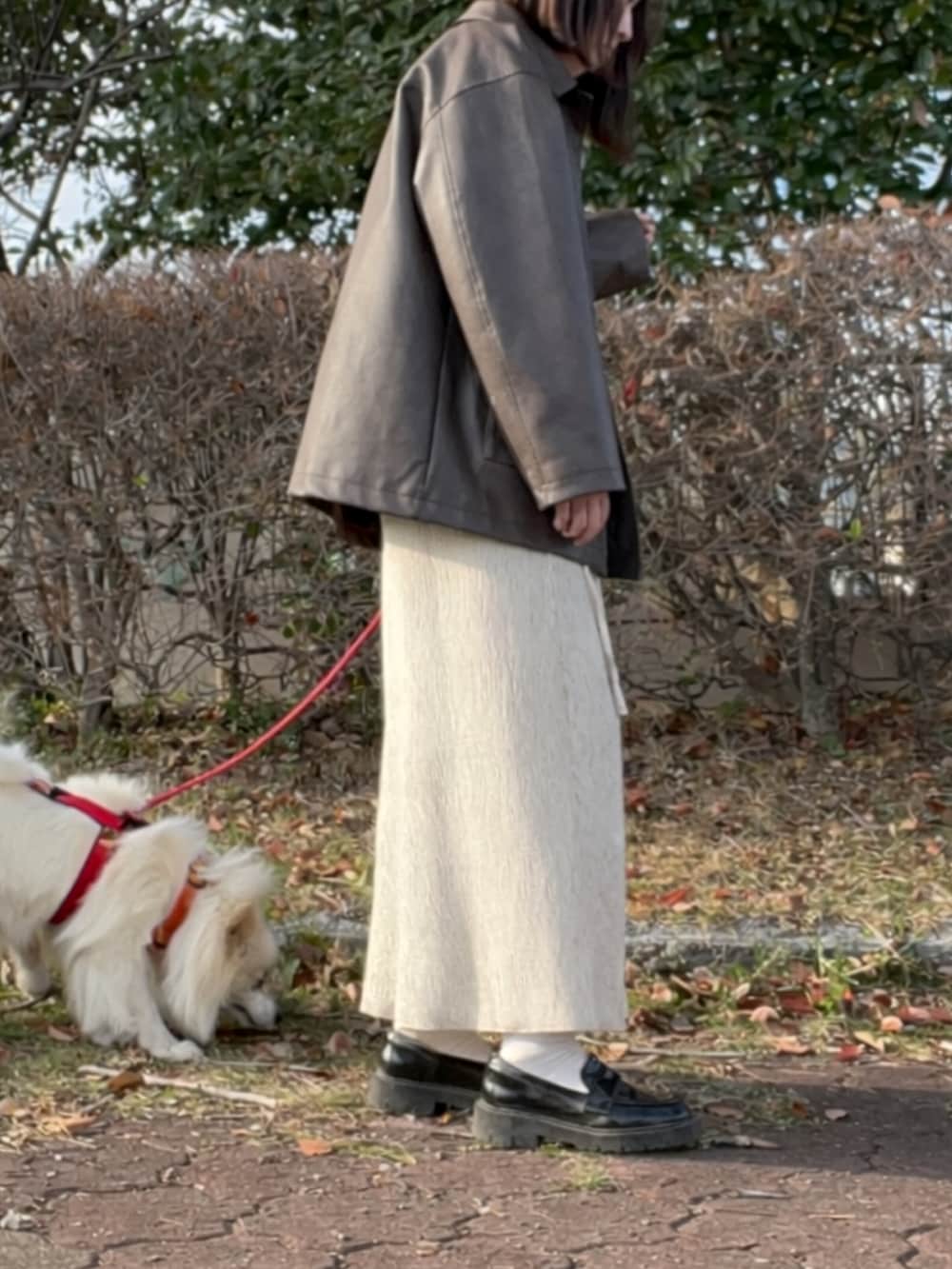 ホワイト系のワンピース、ブラウン系のステンカラーコート、ブラック系のローファーを着用したレディースの春コーディネートの2枚目の写真