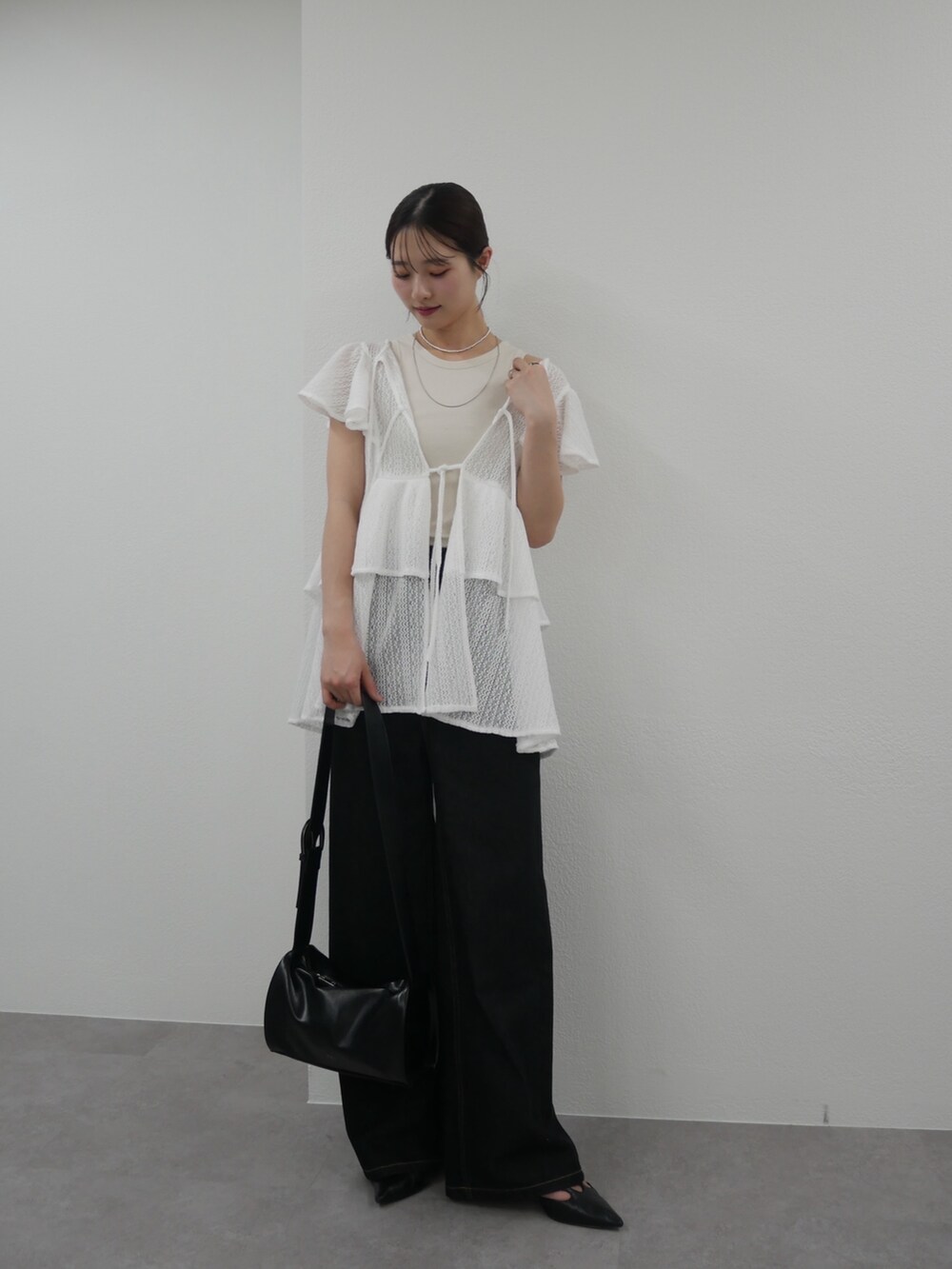 ホワイト系のチュニック、ホワイト系のタンクトップ、ブラック系のデニムパンツを着用したレディースの春コーディネートの2枚目の写真