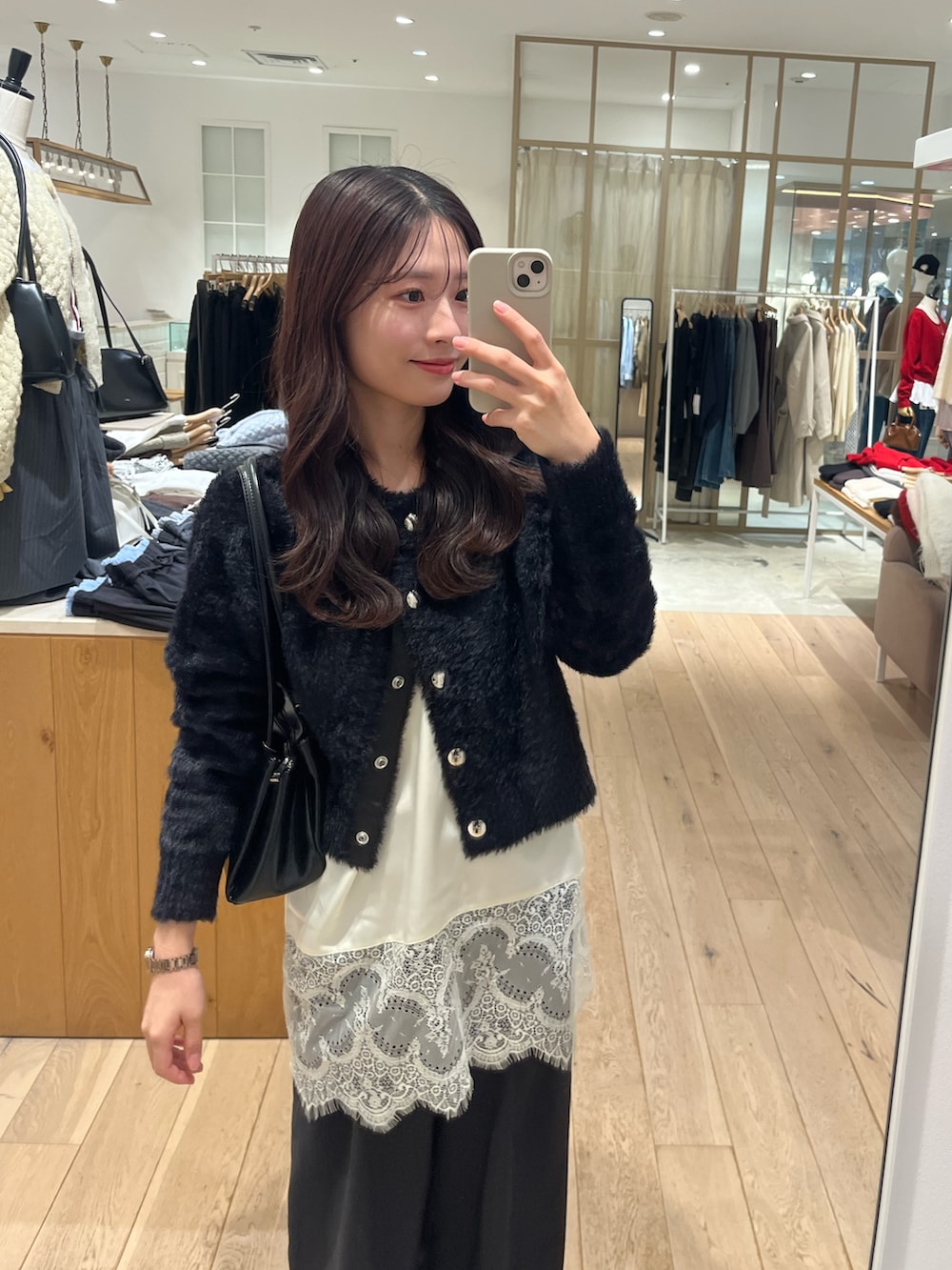 ブラック系のブーツ、ブラック系のカーディガン/ボレロ、ホワイト系のキャミソールを着用したレディースの秋コーディネートの2枚目の写真