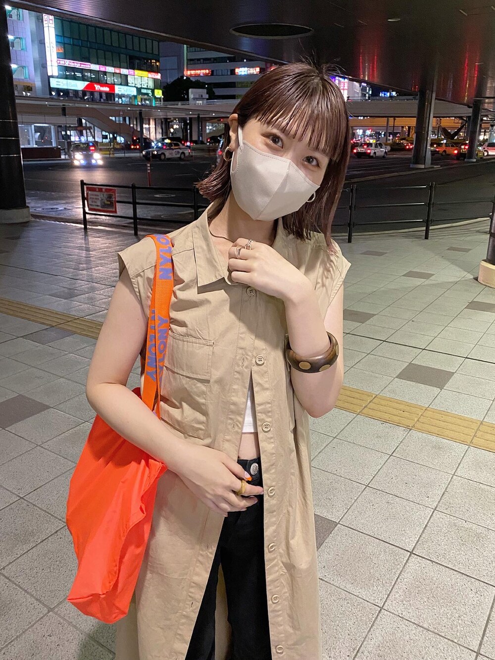 オレンジ系のトートバッグ、ベージュ系のシャツワンピースを着用したレディースの夏コーディネートの2枚目の写真